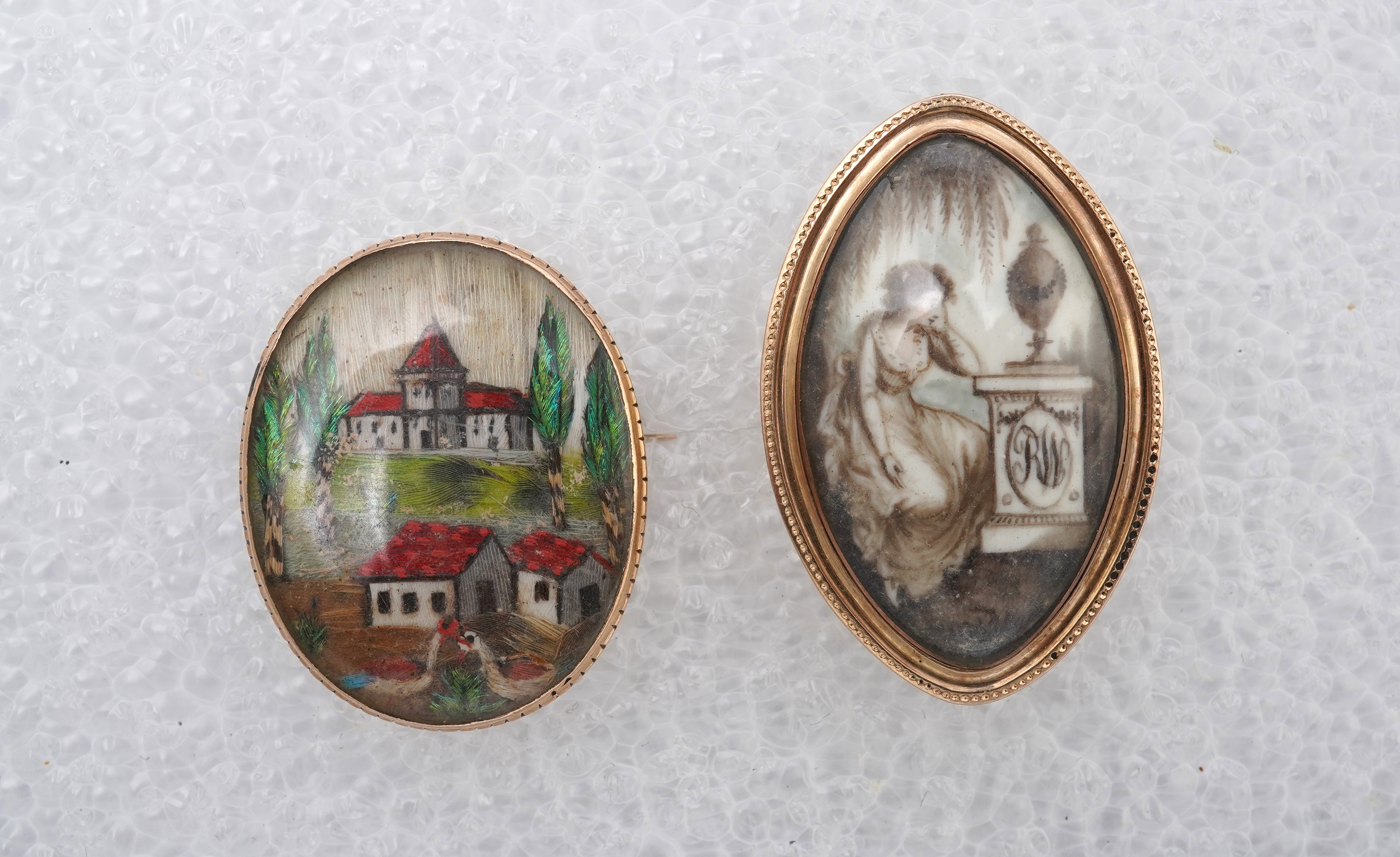 A George III ivory mourning brooch, circa 1786, and a feather work brooch, 19th century